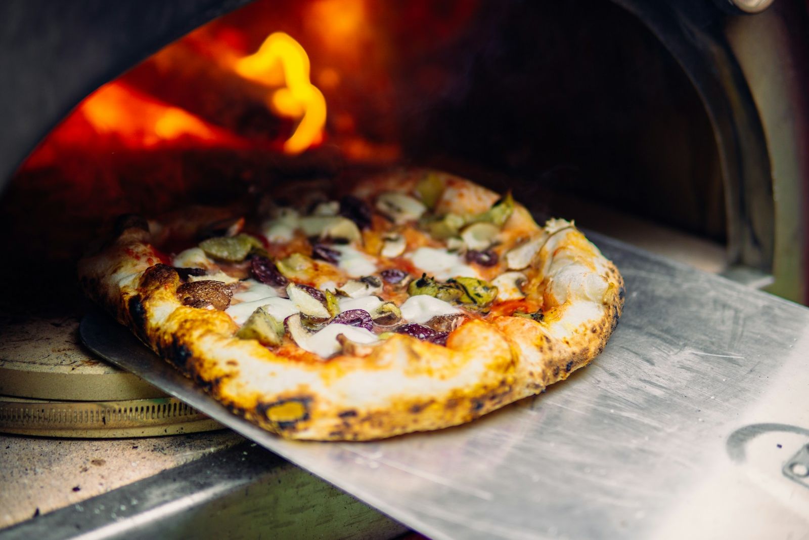 Pizza emerging from a wood-fired oven