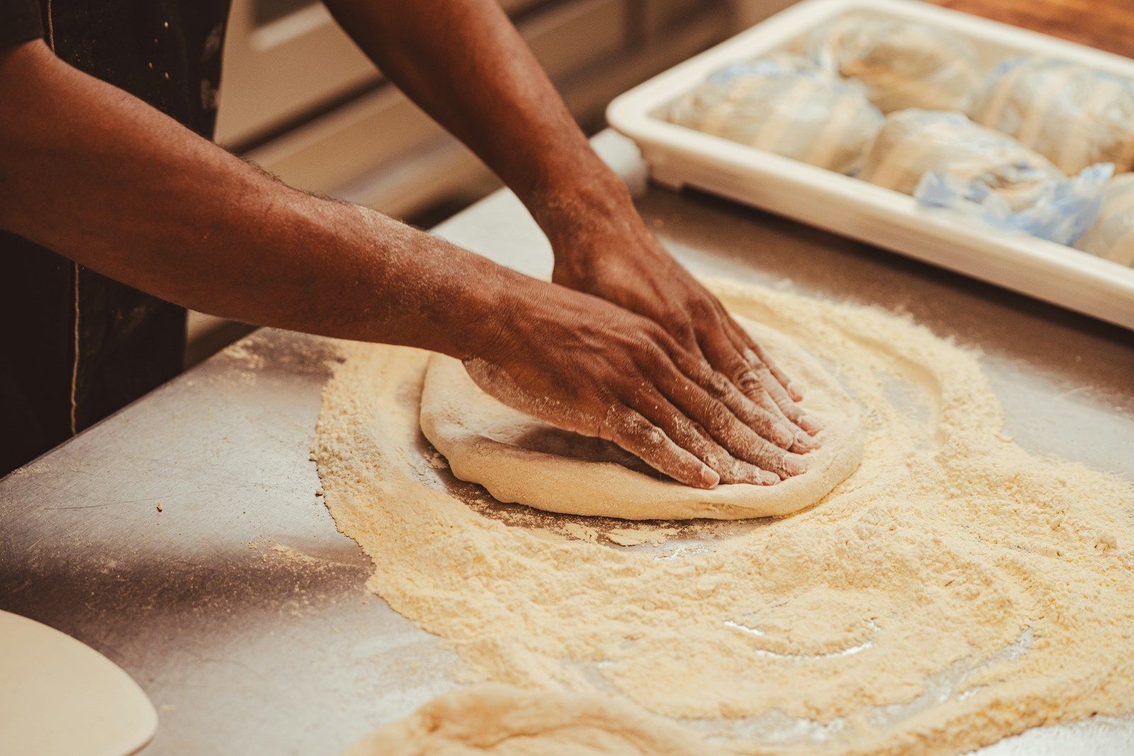 Hands shaping pizza dough on a floured surface